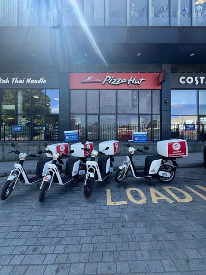 Four Pizza Hut-liveried Otto mopeds lined up outside a Pizza Hut Delivery branch